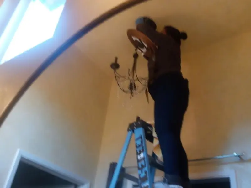 Electrician installing a chandelier in a Lee residence